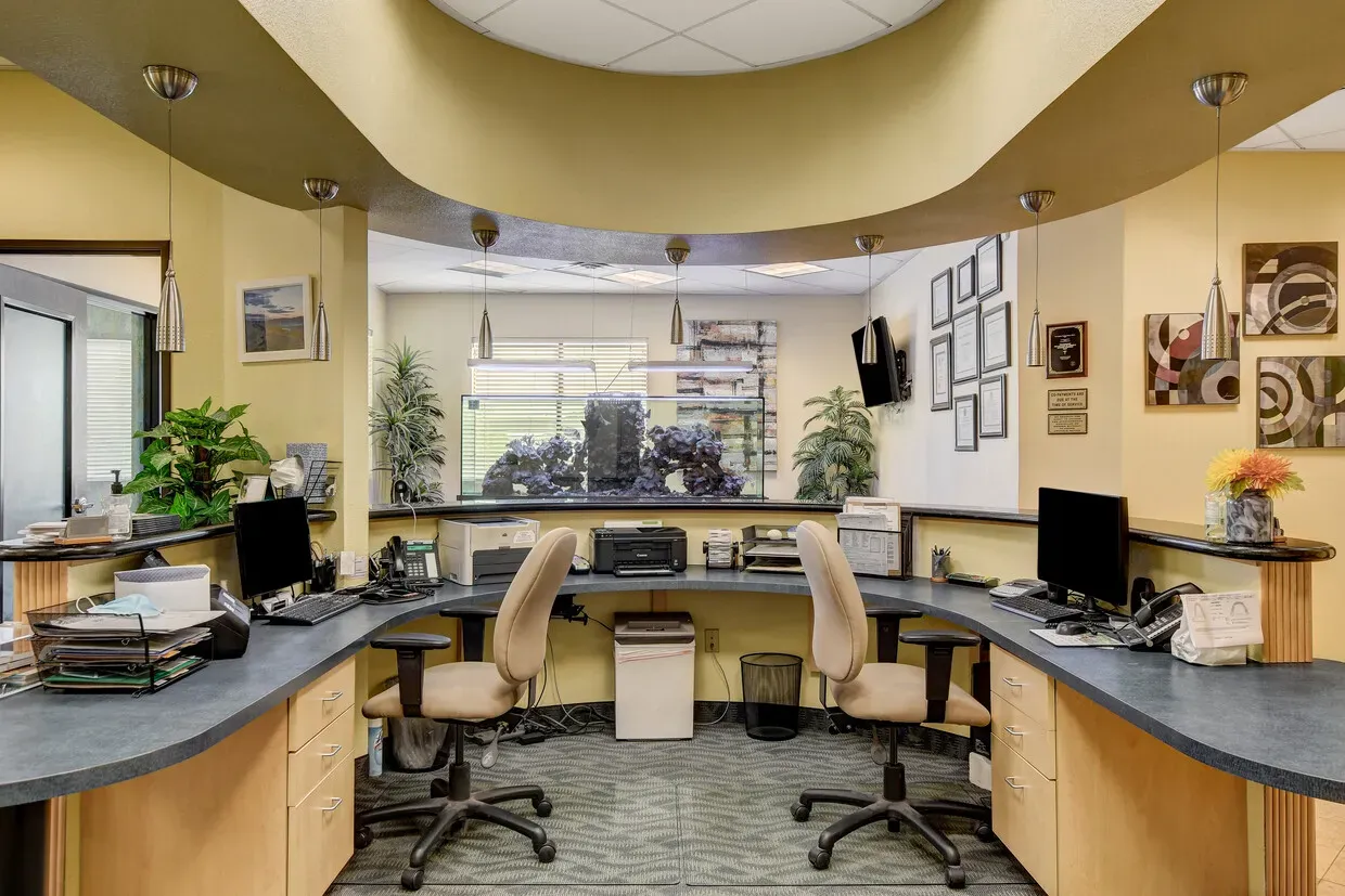 Front office workstations behind the reception desk, with a saltwater aquarium in the window